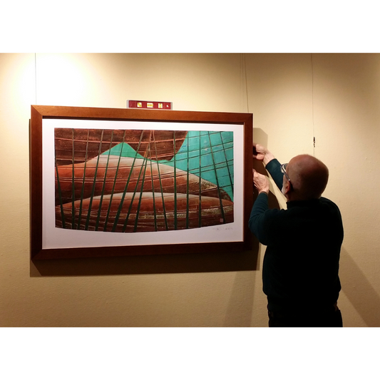 Person adjusting a framed artwork on a wall
