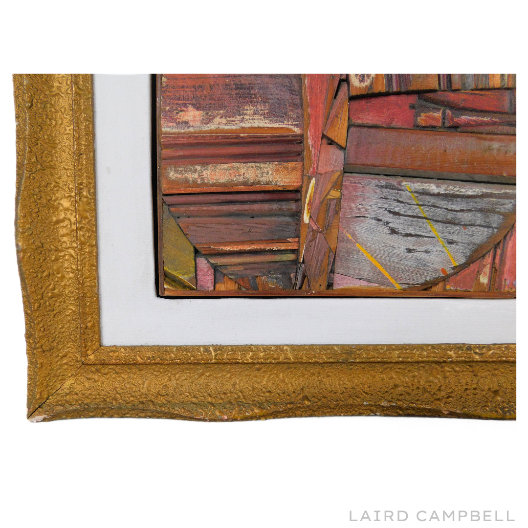 Close up of wooden assembled artwork in gold frame, featuring the artist's name 'Laird Campbell'.